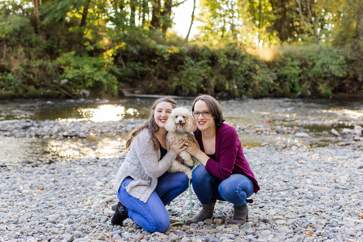 PNW LGBTQ river engagement session at Snohomish river happy couple hugging and smiling with dog colorful fun photo by Joanna Monger Photography