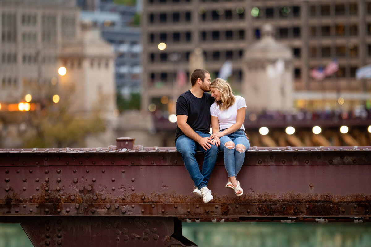 engaged couple wearing jeans and t-shirts on red Chicago river bridge 