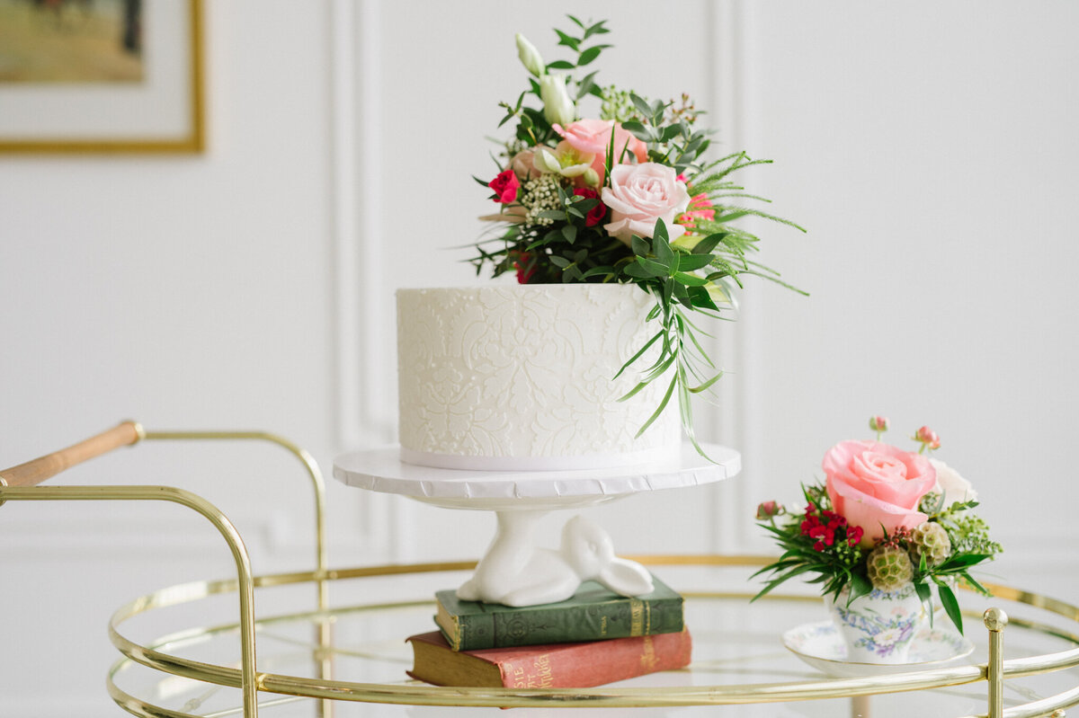 Gorgeous and classic one-tiered wedding cake topped with pink florals and greenery, by Yvonne's Delightful Cakes, classic cakes & desserts in Calgary, Alberta, featured on the Brontë Bride Vendor Guide.
