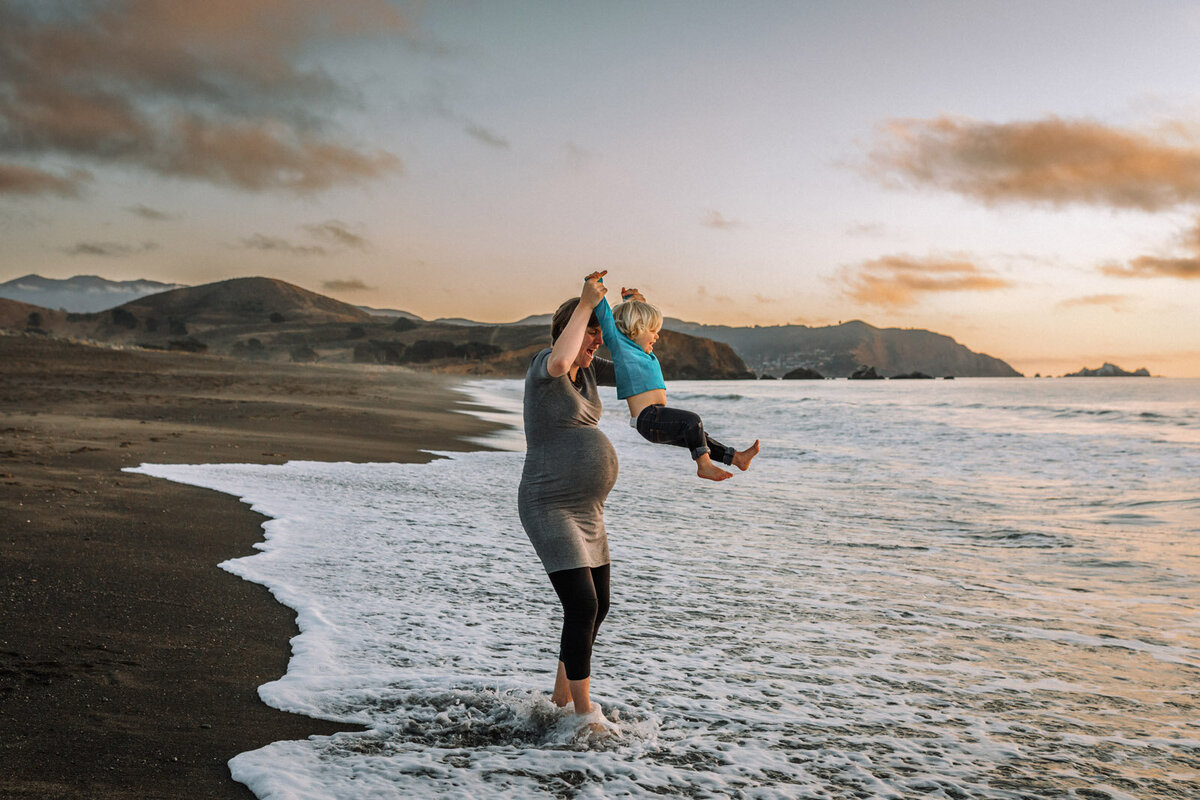 pregnant woman swinging son out of the ocean at Pacifica beach