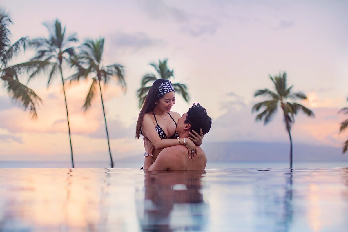 Couple in the Four Seasons infinity pool embrace in the water while their photography session takes place by Love + Water