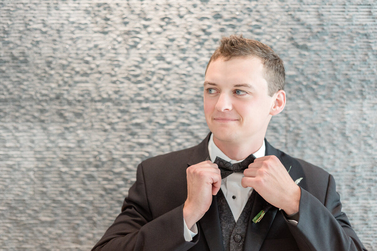 A groom adjusting his bow tie and getting ready for his luxurious wedding.