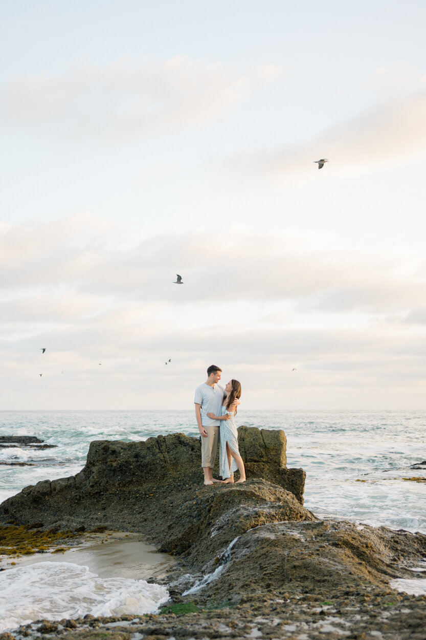 couple standing on a rock in the ocean