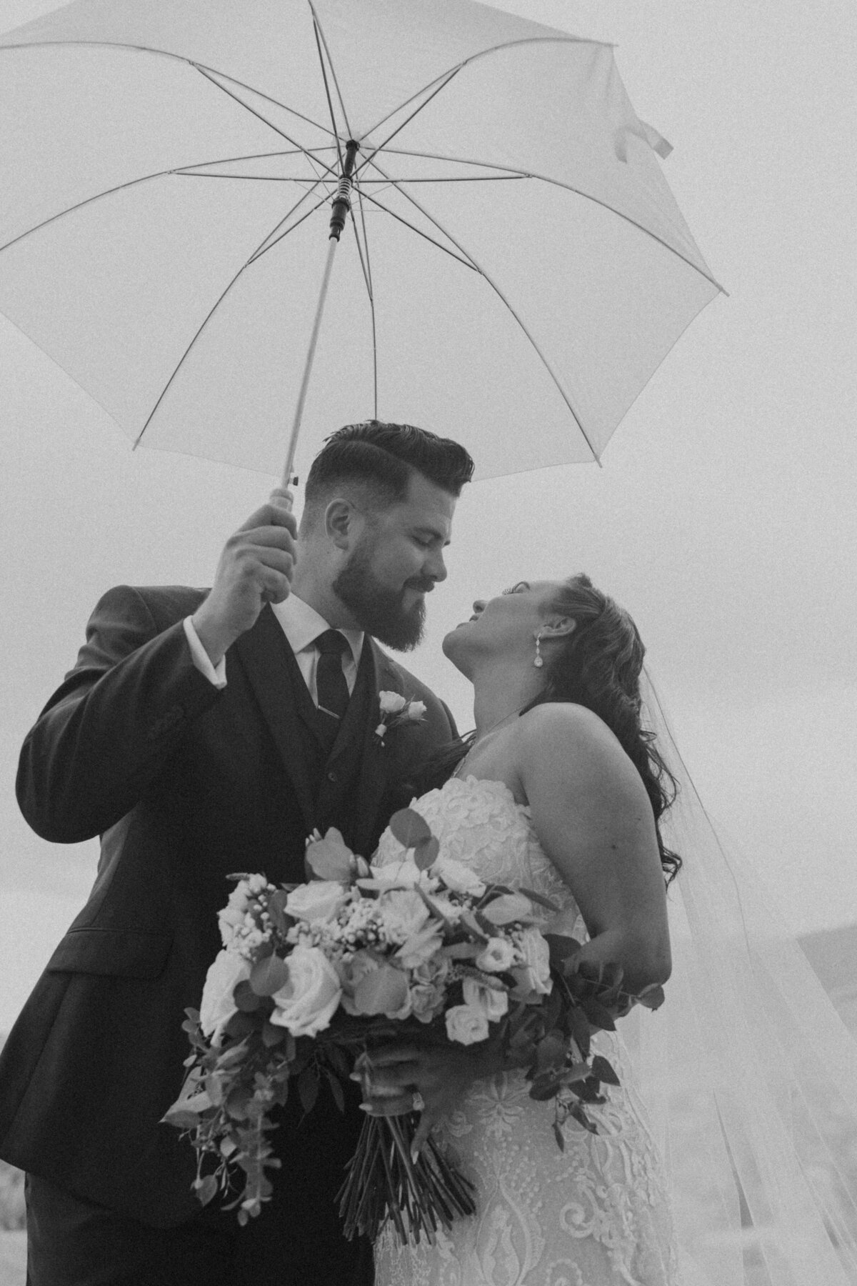 black and white photo of bride and groom in the rain