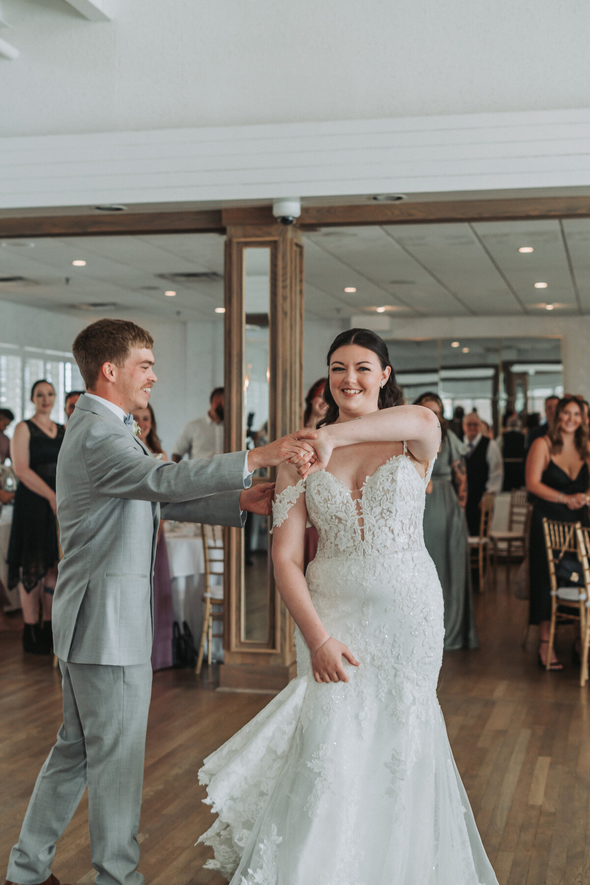 Bride smiles brightly as the groom twirls her during their first dance surrounded by guests at the Lesner Inn in Virginia Beach, Virginia.