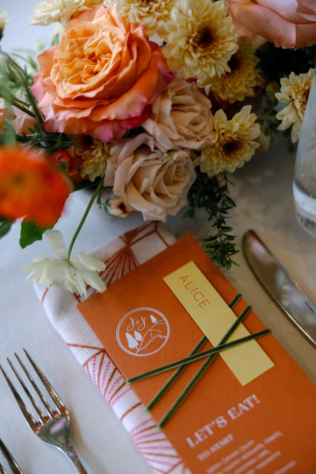 custom calligraphy wedding menu on a printed cloth napkin with florals and flatware representing full service design and calligraphy by Life in Letters.