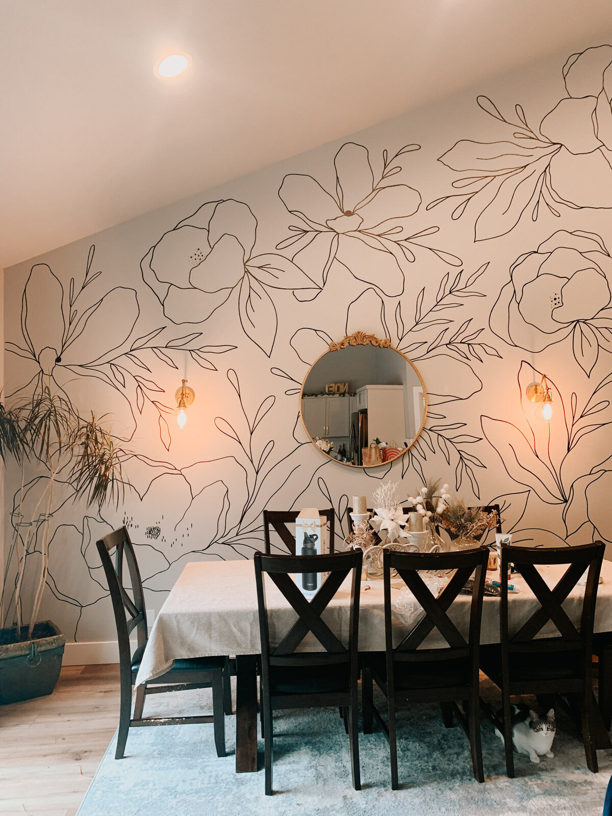 A dining room setting with a table and chairs featuring a back wall with modern florals drawn on it representing full service design and calligraphy by Life in Letters.