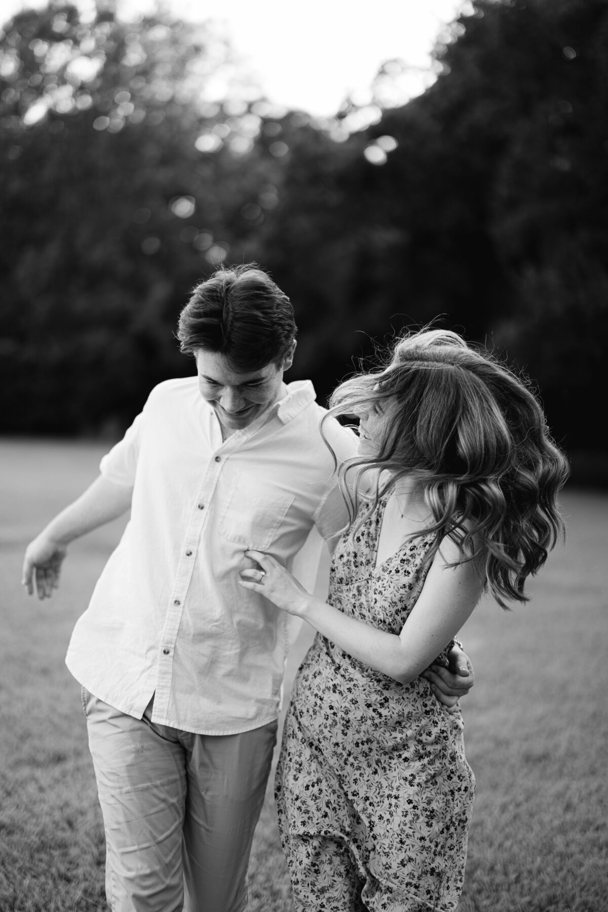 Couple running and playing joyfully during their engagement session at UL Alumni Center, captured by Morgan Alysse, Lafayette wedding photographer.