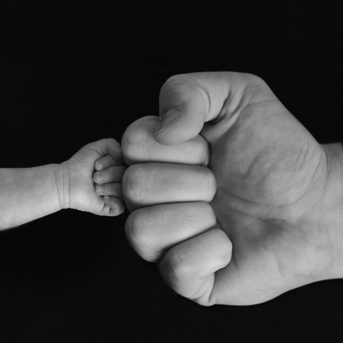 A bold and symbolic macro moment—a newborn’s first fist bump with dad, where strength meets new life.