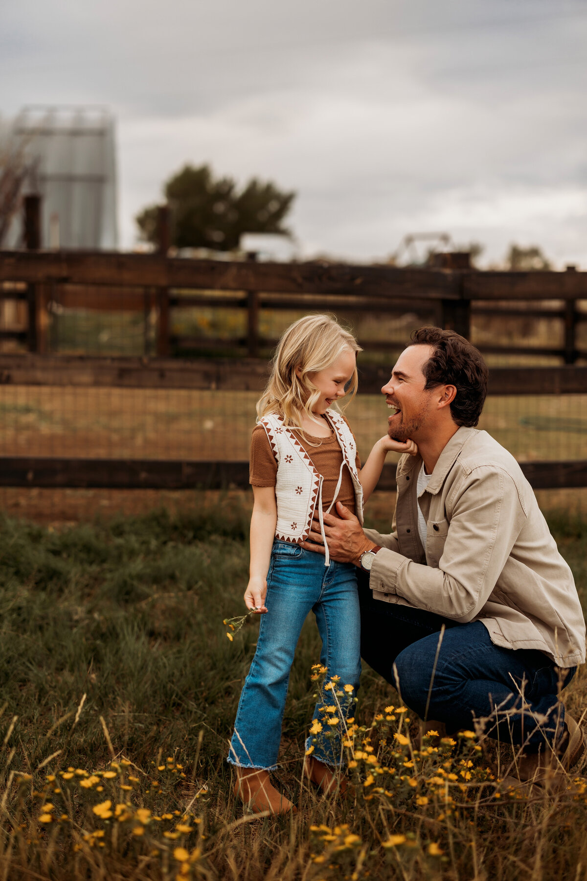 Dad leaning down to young daughter in a field of yellow flowers