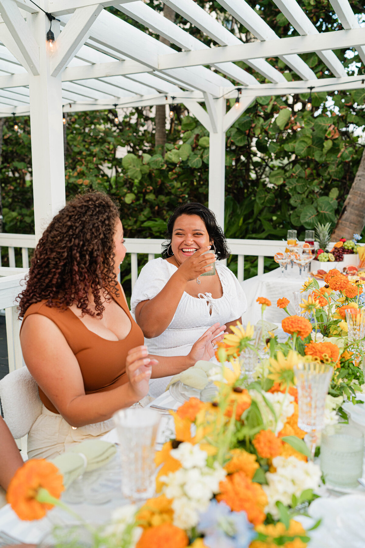 girlfriends laughing at adorned beach brunch table