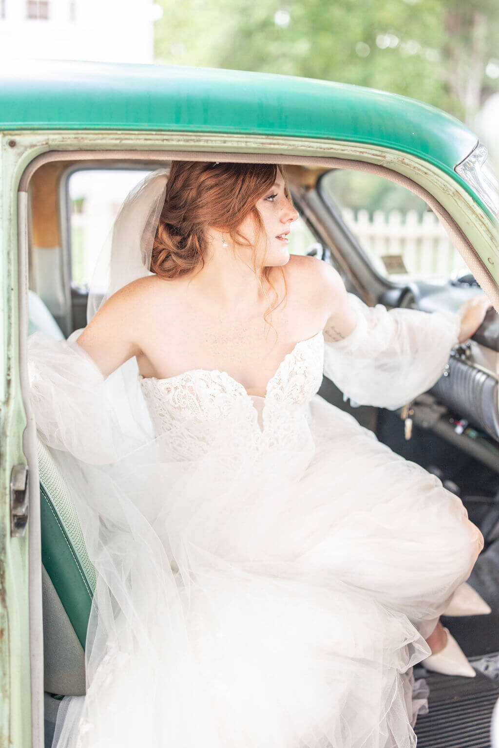 Glamorous bride adjusting her gown in a vintage car, preparing for her timeless and faith-filled wedding celebration.
