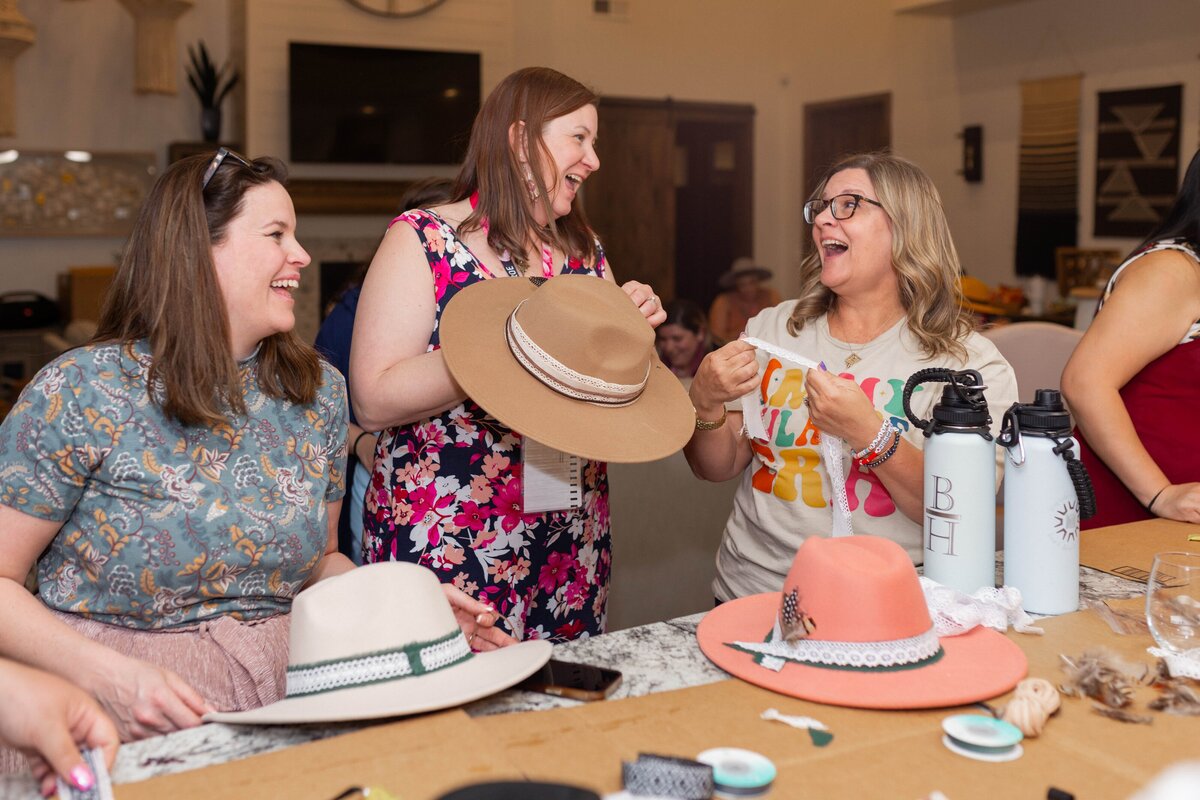 three woman laughing together while doing a craft