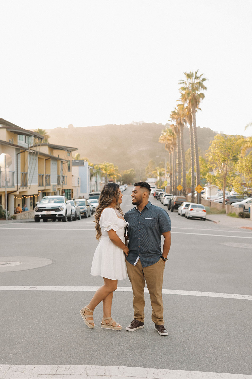Engaged couple walking hand in hand down a beach town street