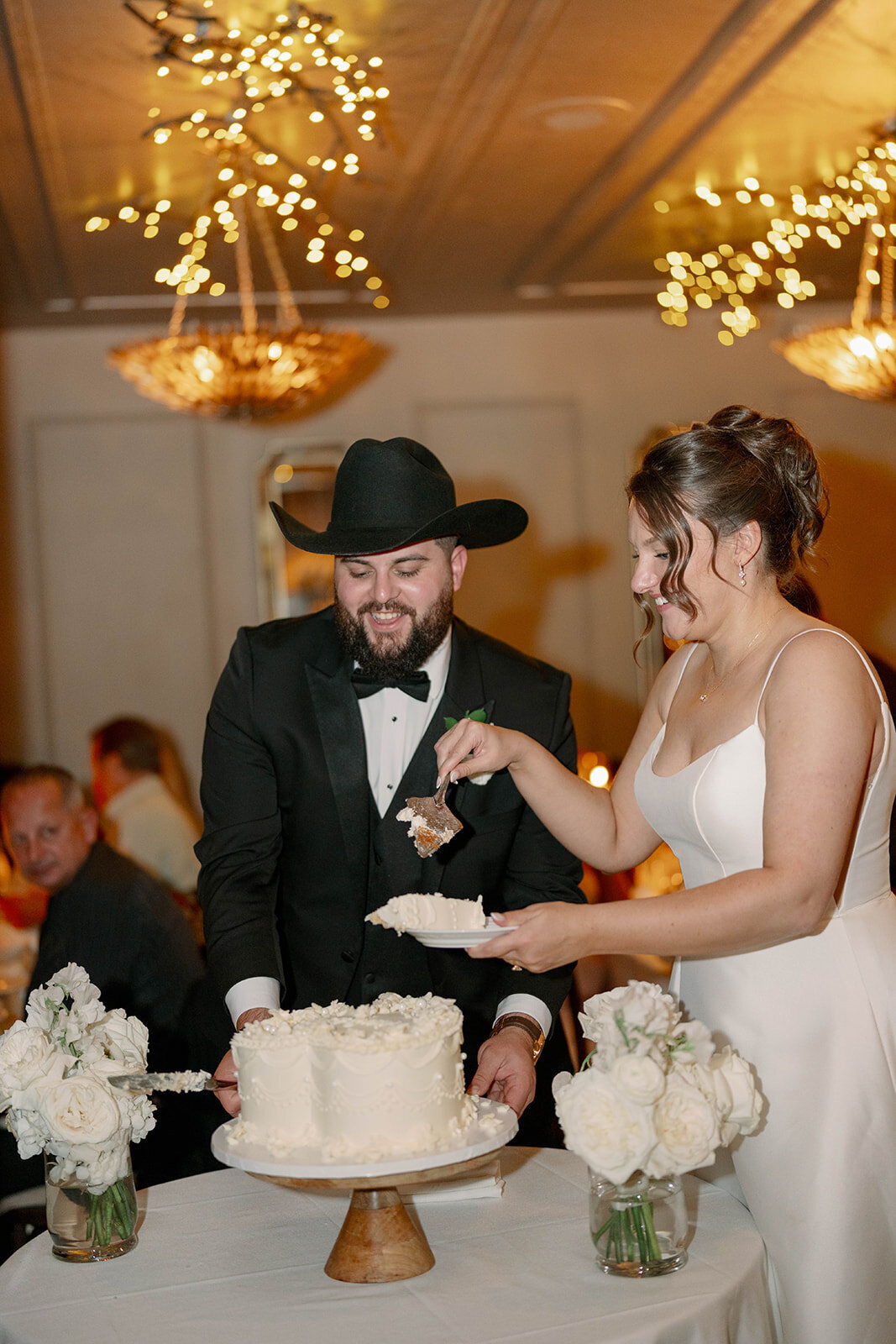 Bride and groom cutting a white wedding cake during their Café Cortina reception in Michigan.