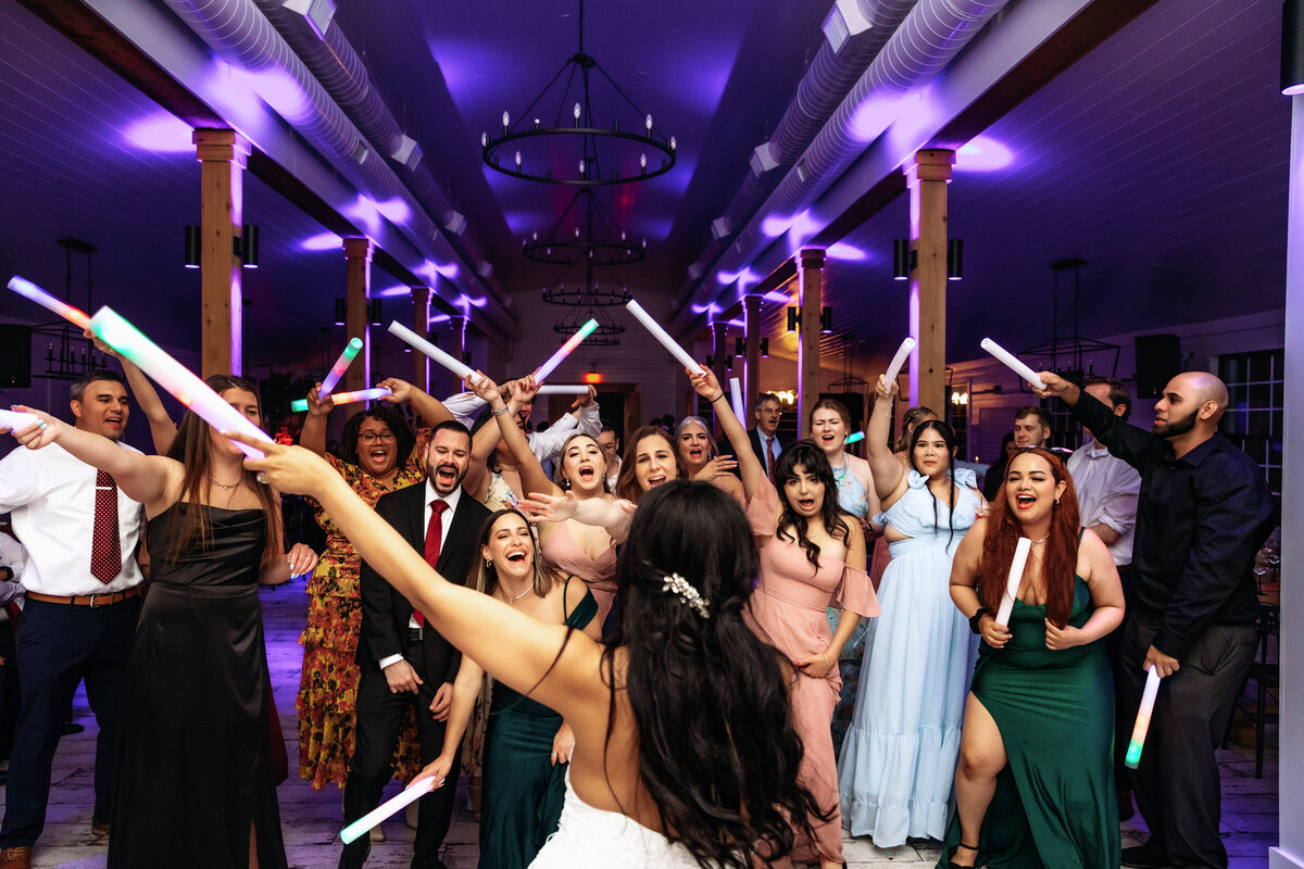Shannon Lee, from Love Like Wild Photography, captures a lively group of wedding guests celebrating with glow sticks on the dance floor.