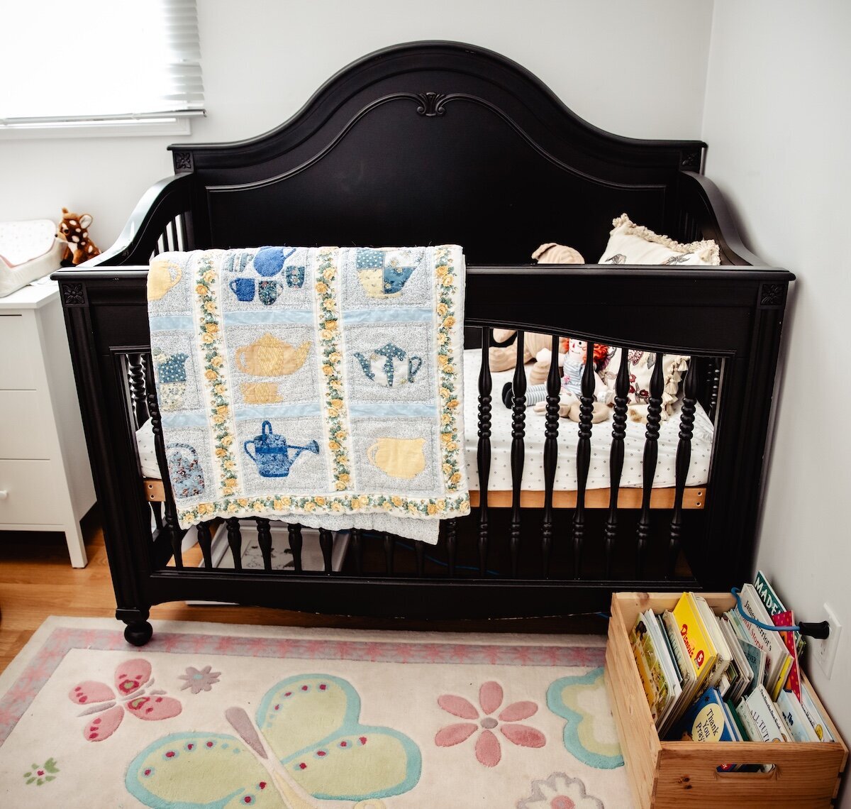 A black crib in a little girl nursey