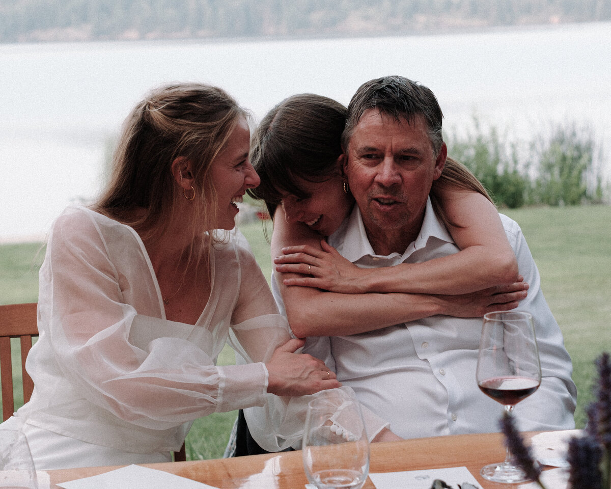 daughters hugging their dad at the reception table