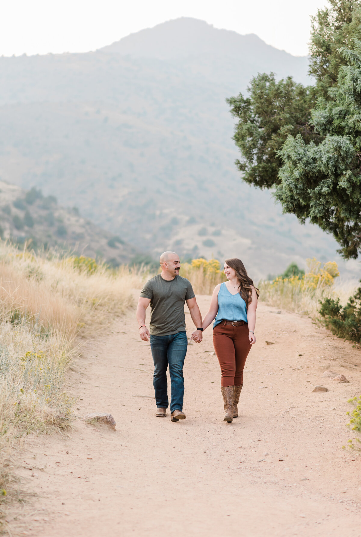 colorado engagement photos by denver engagement photographer with man and woman holding hands and walking down a dirt path together