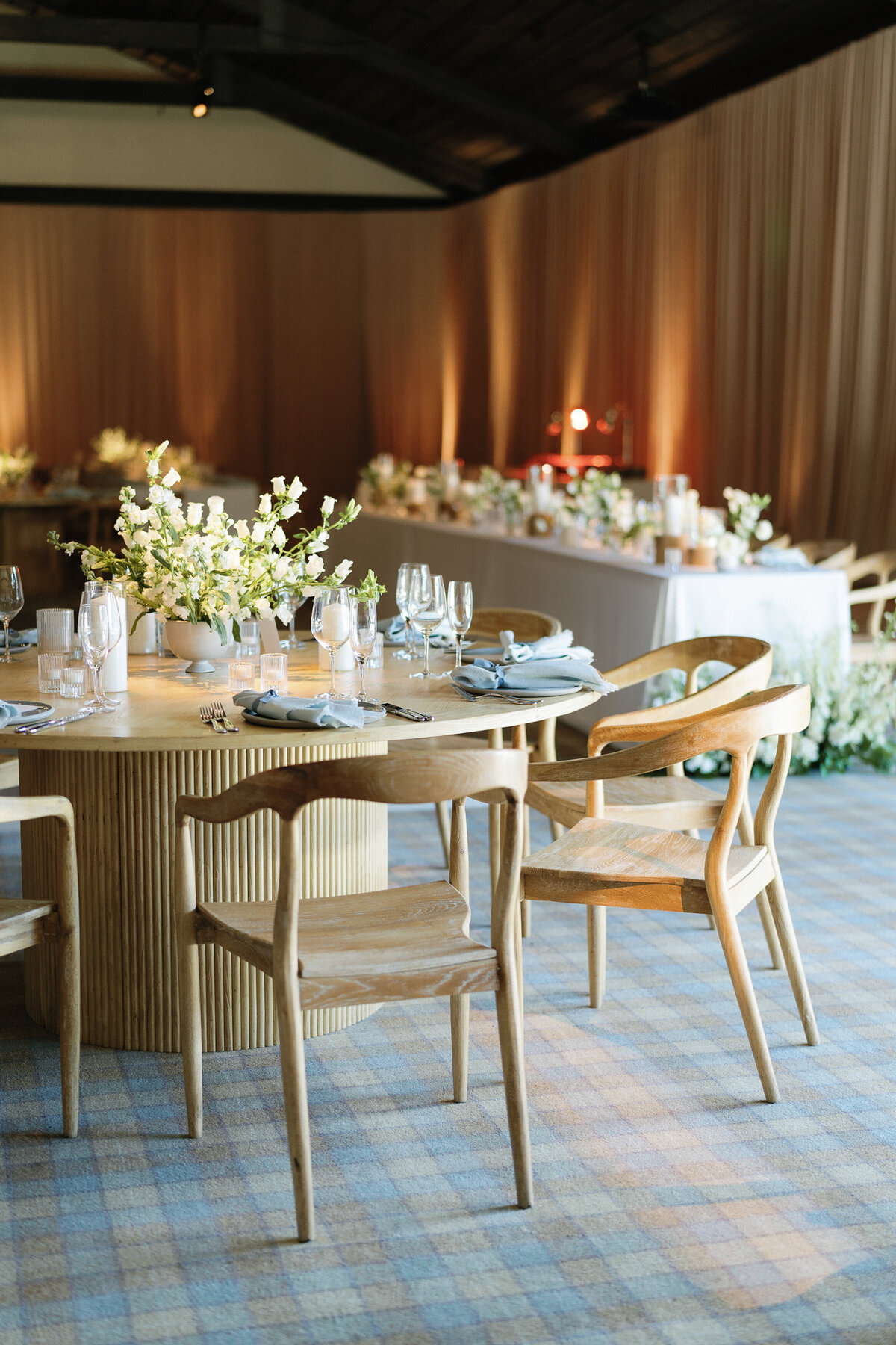 Modern wedding table design, light wood table and chairs, light blue napkins and delicate white flowers decorate the table.,