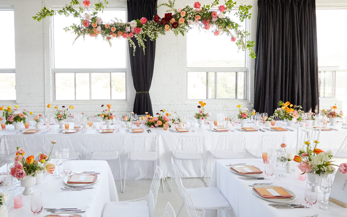 A floral arrangement suspended against the white brick walls of L’Eloi decorates a wedding reception.