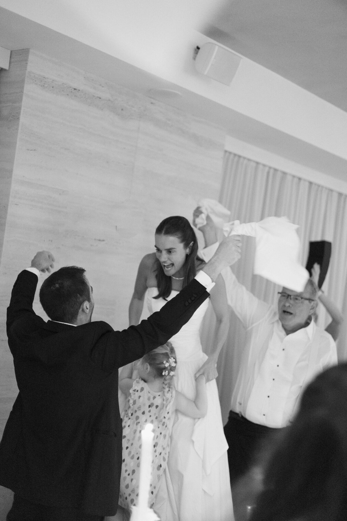 Bride standing on chair with napkin during traditional Italian wedding cheer


