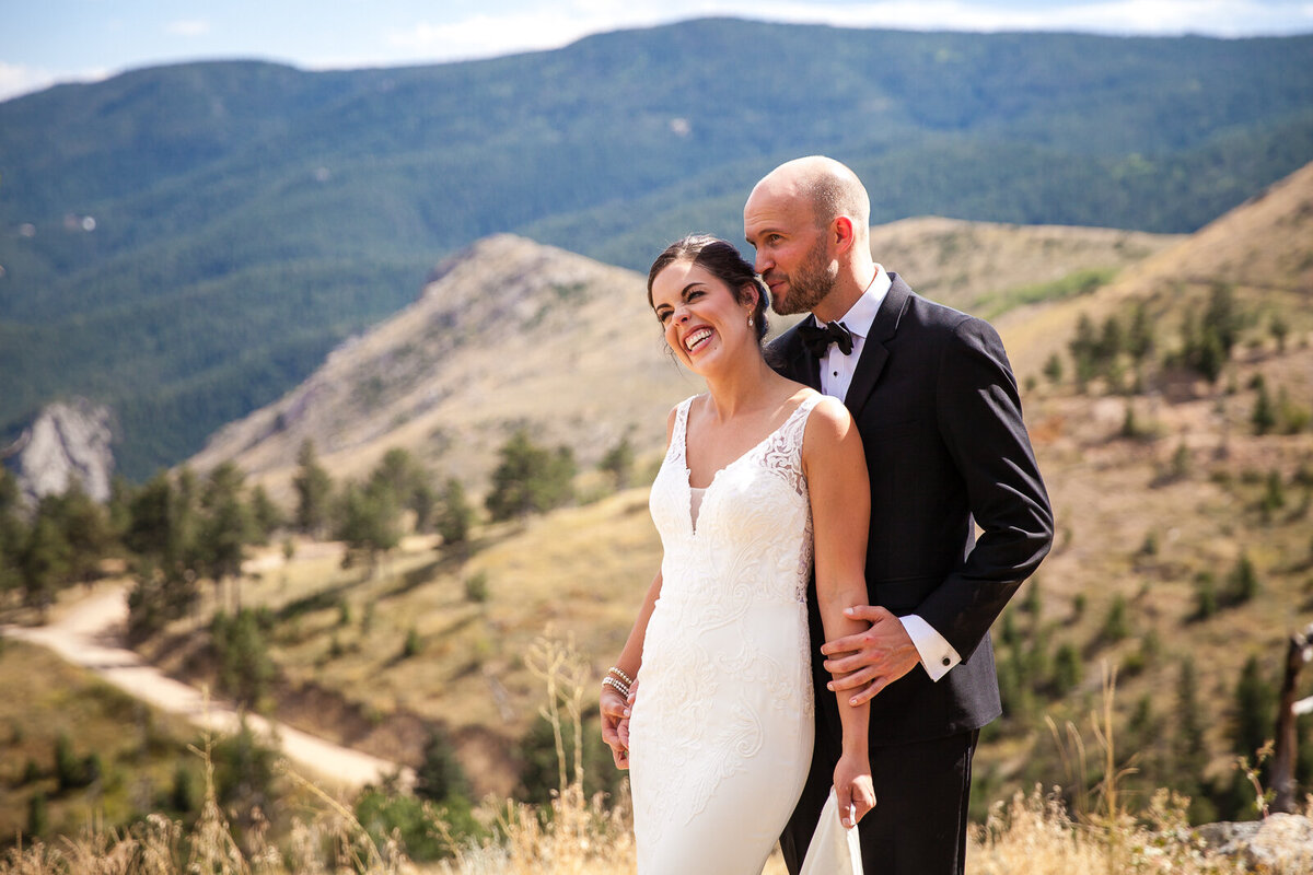 Woman in a wedding dress and man in a suit stand in the mountains of Boulder, Colorado.