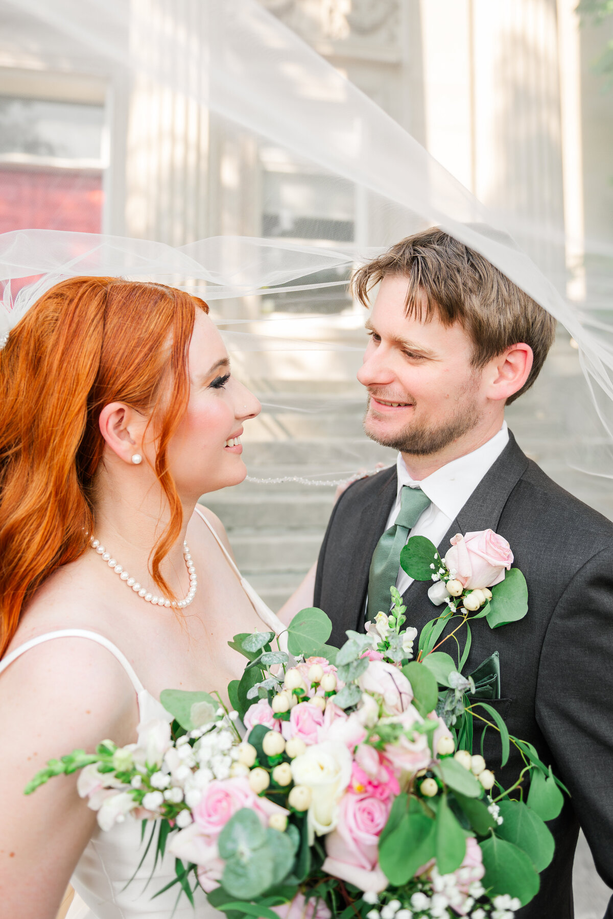 Bride and groom under veil looking at each other in love