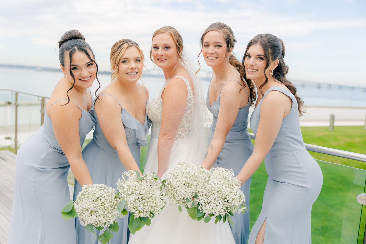 bride and bridesmaids in powder blue in front of Newport bridge