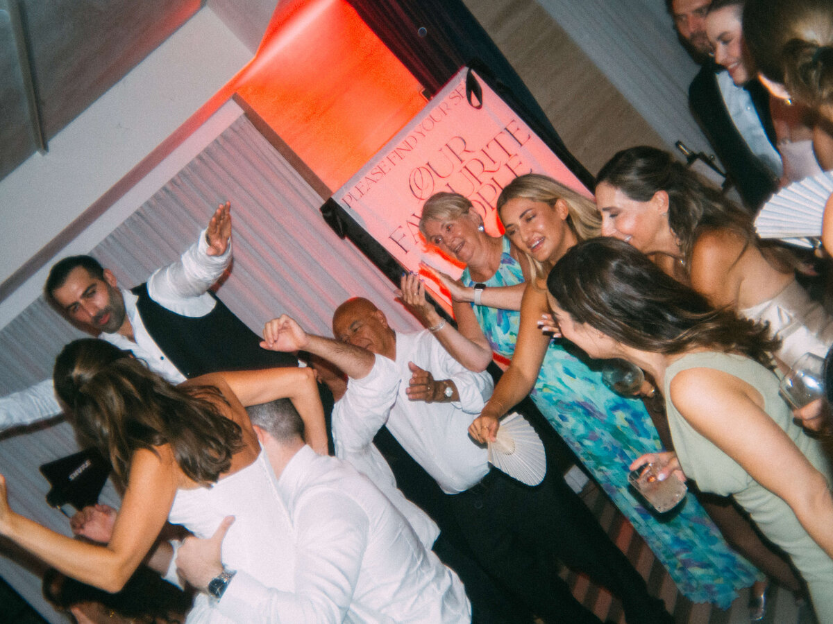 Guests jumping and cheering in energetic dance circle at wedding

