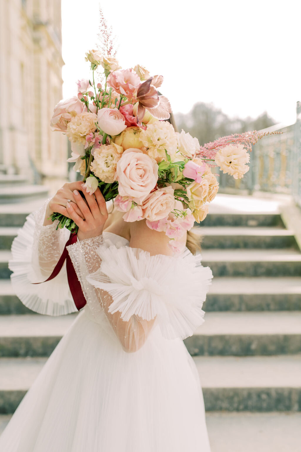 Bride hiding behind floral bouquet  on the chateau de sceaux in France.