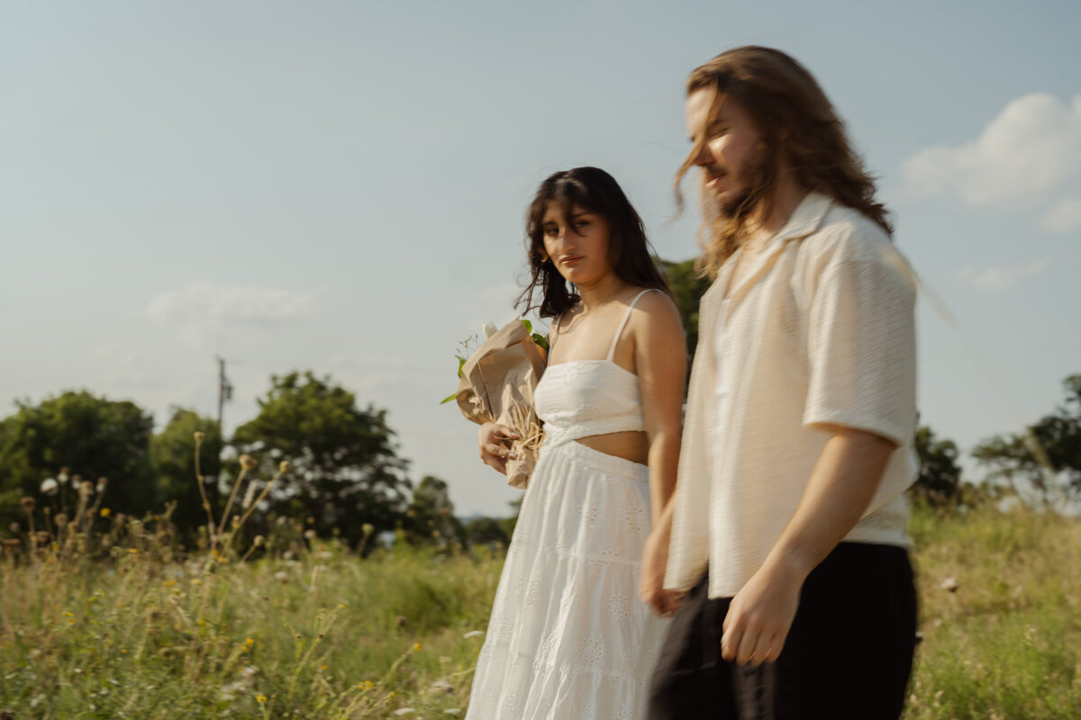 A playful, candid shot of a couple strolling hand in hand through the park near White Rock Lake, capturing the essence of love.