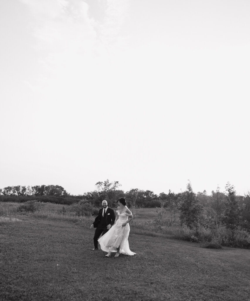 Bride and groom holding hands walking together through a field, image by Ninth Avenue Studios, authentic and intimate wedding photographer in Calgary, Saskatoon, and Vancouver. Featured on the Bronte Bride Vendor Guide.