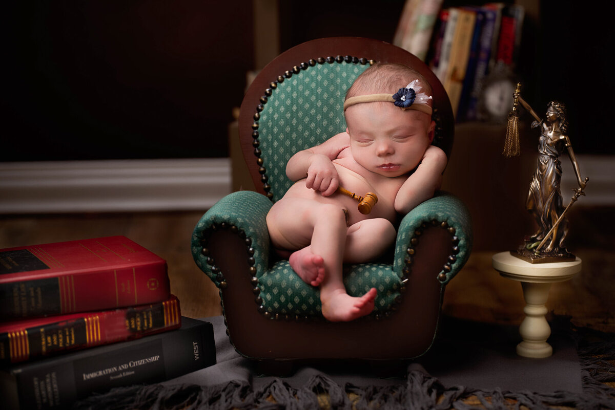 Newborn nestled among open law books in a lawyer-inspired setup, captured in Overland Park, Kansas. Perfect for families who love storytelling and creative newborn photography themes.