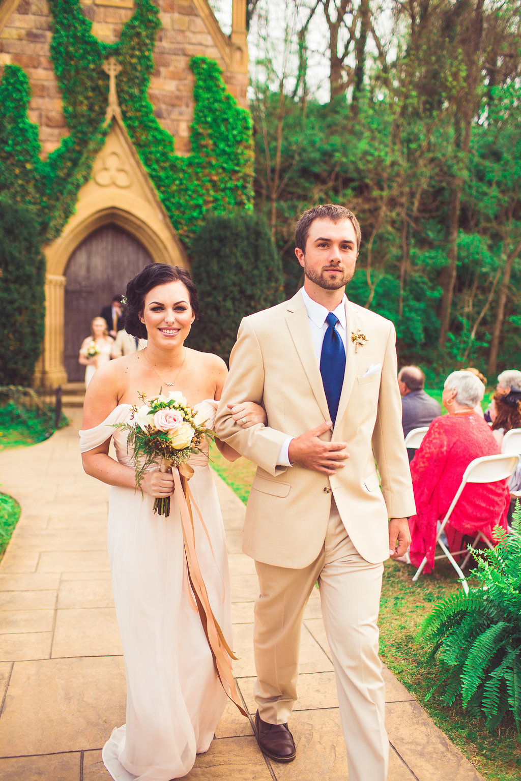 Wedding Photograph Of Bridesmaid Holding a Bouquet and Groomsman in Light Brown Suit Walking Down The Aisle Los Angeles