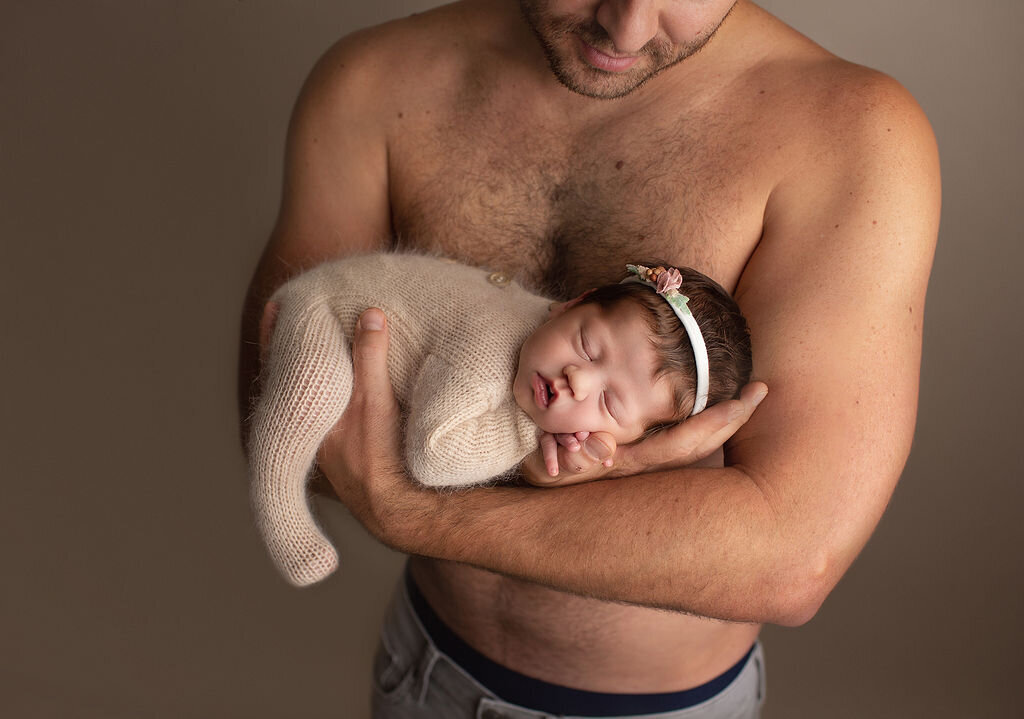 brand new baby posed in her dads arm in denver newborn photography studio