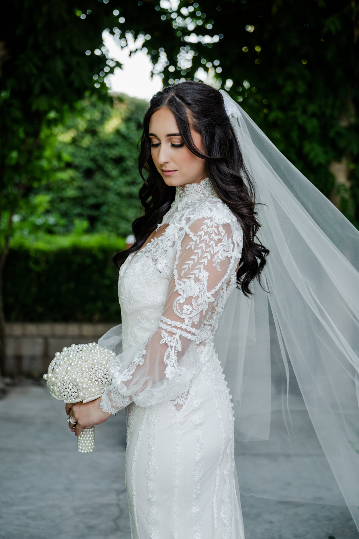 Close-up of a bride admiring her classic white bouquet on her wedding day.