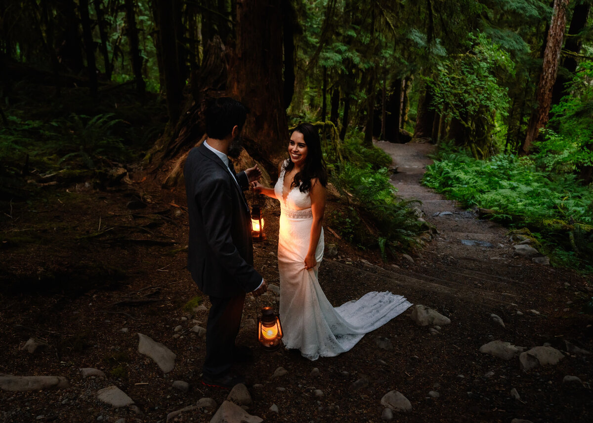 A couple smiles at each other in their wedding attire  as they have an intimate first look during their olympic national park elopement