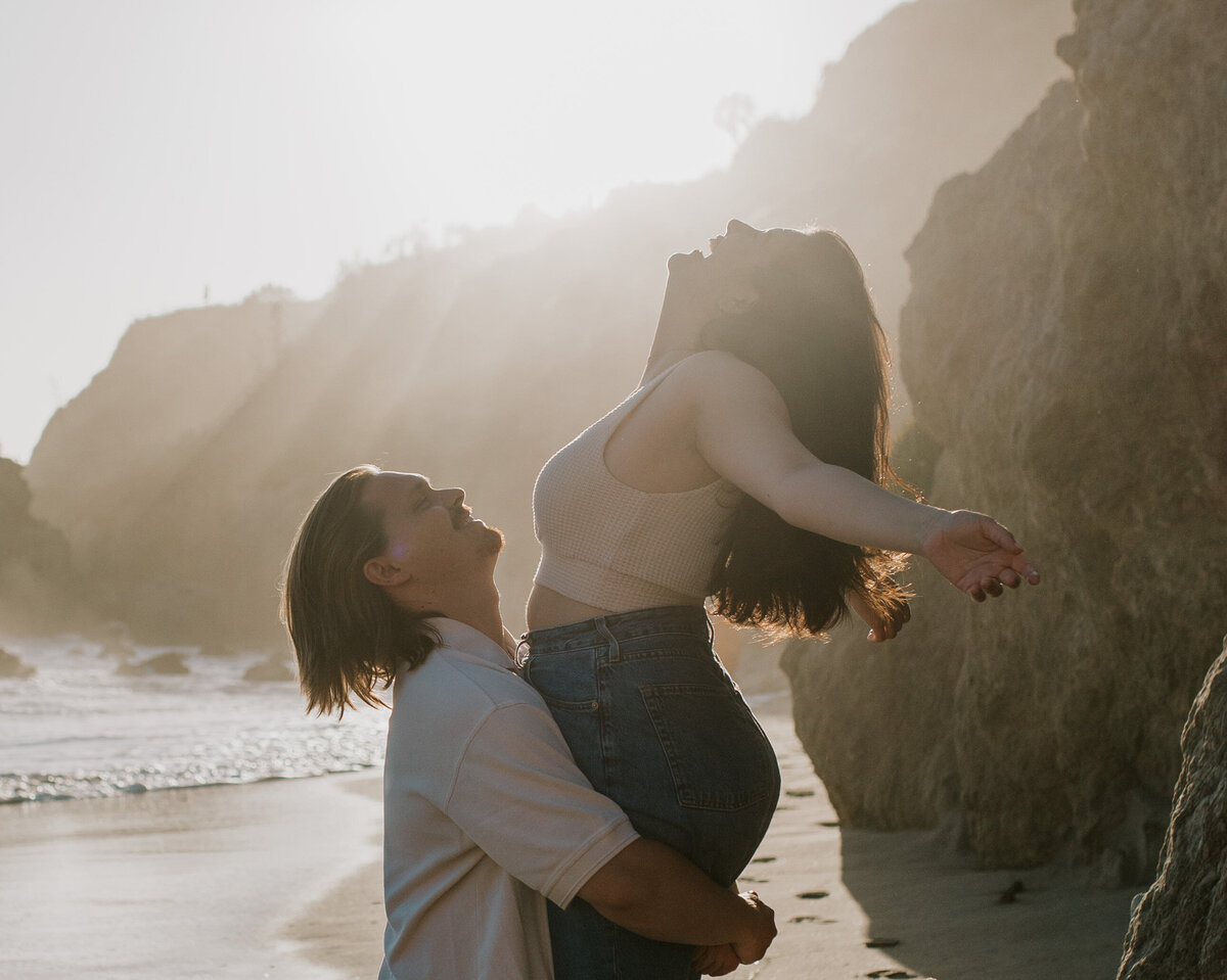 Couple sharing a moment on a rocky coastline, adventurous engagement session.