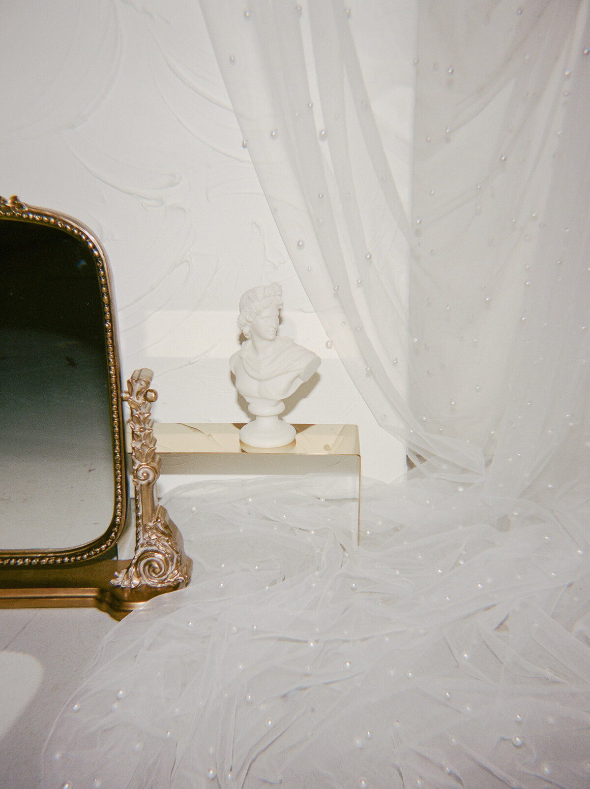 glimmering gold anthropologie mirror, ornate, ivory bust sculpture candle, florist brand photo details