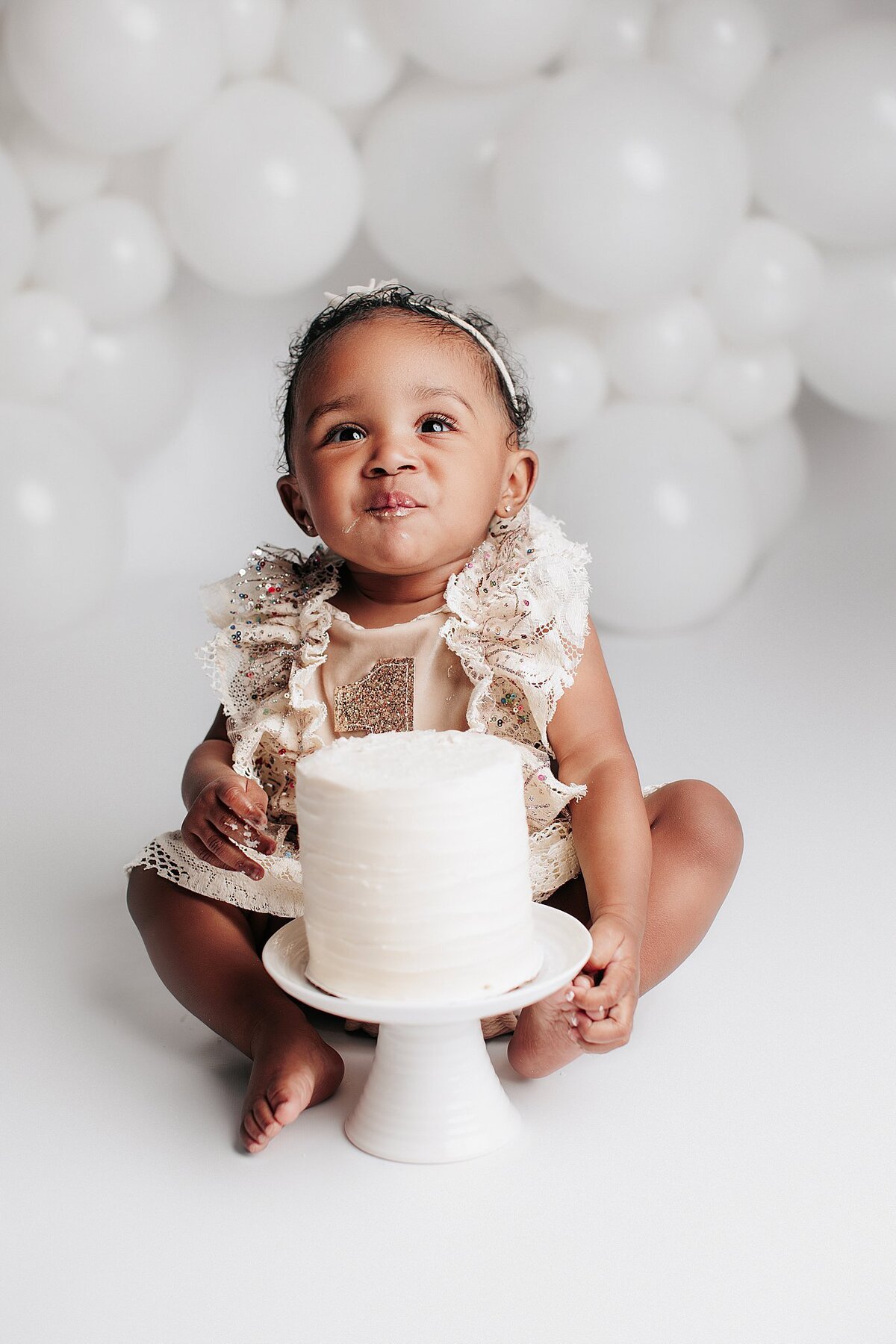 First birthday cake smash setup with balloons and pastel decorations