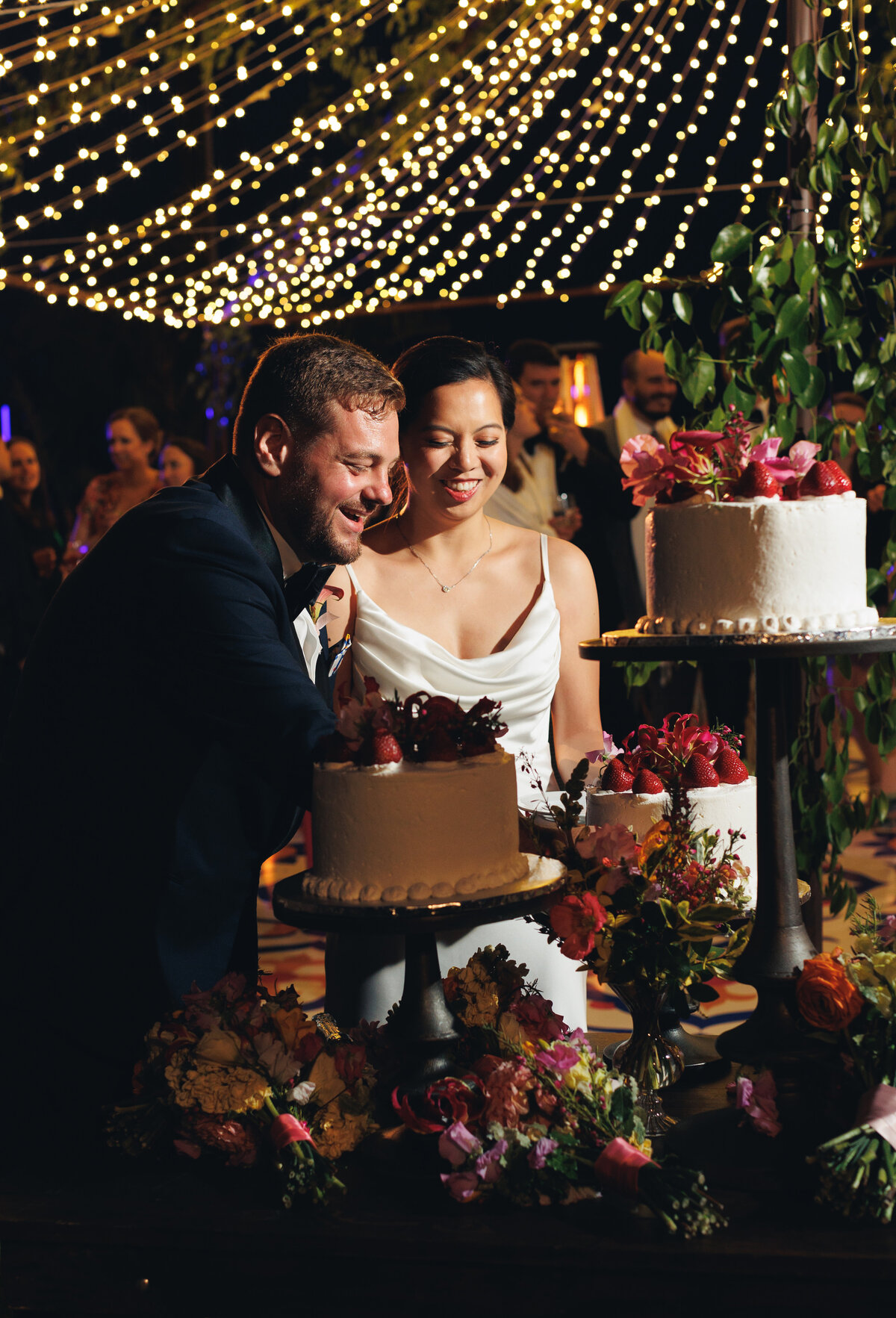 Couple cutting a cake with strawberries