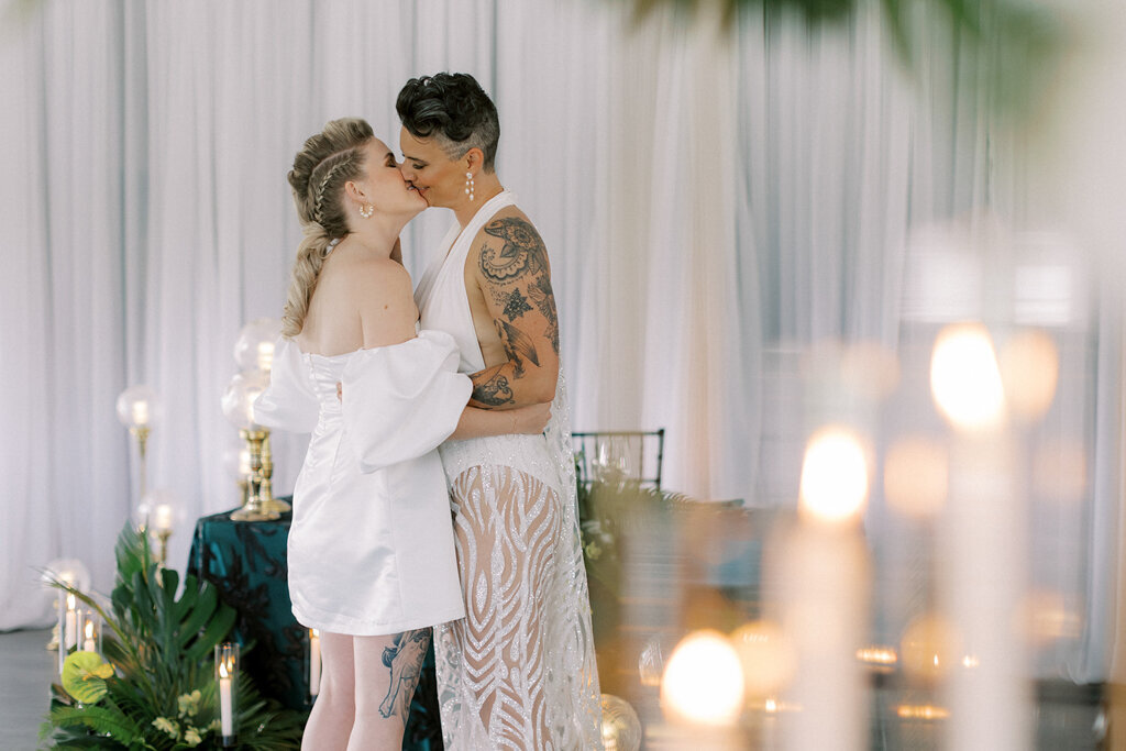 Same sex couple kissing during wedding reception at Sugar Pine Island, a romantic wedding venue in Foothills, Alberta, featured on the Brontë Bride Vendor Guide.