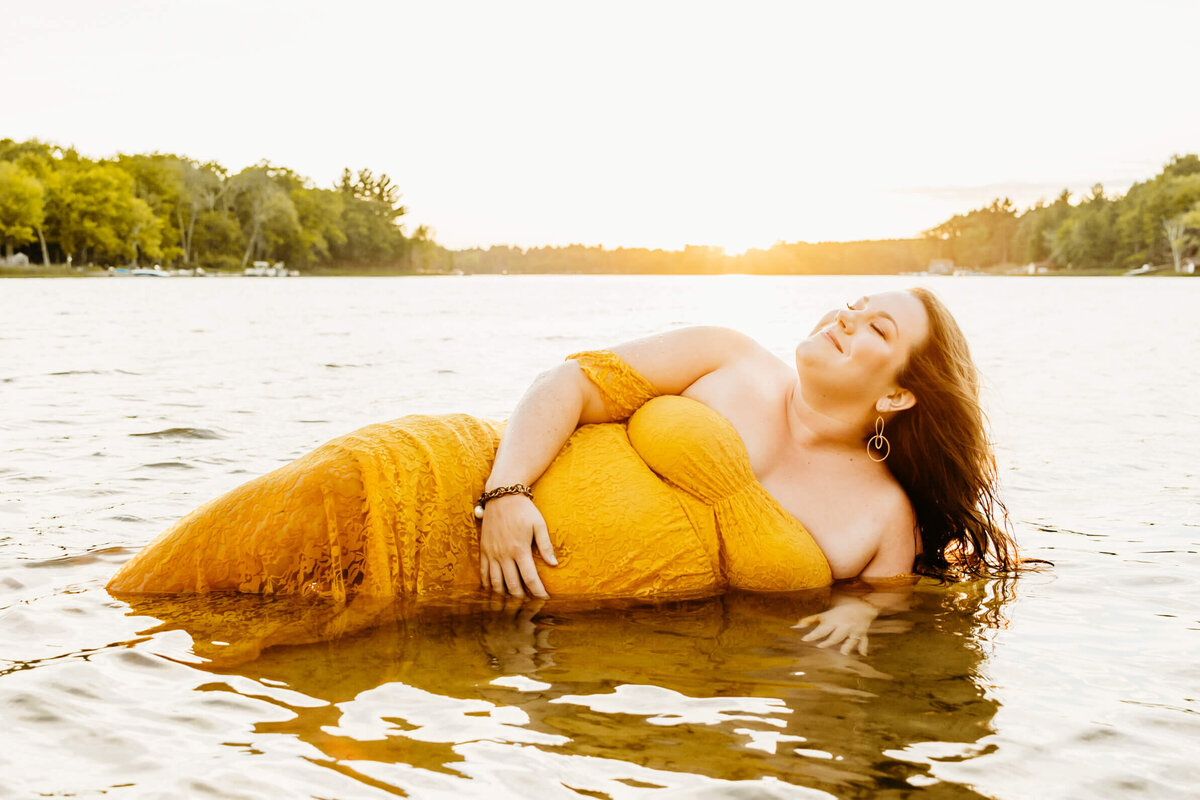 gorgeous pregnant mom laying in a lake at sunset near Green Bay