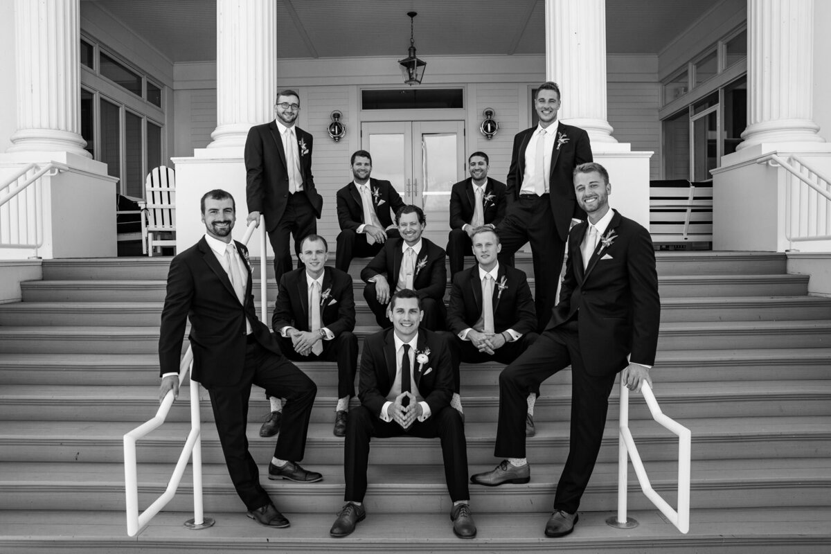 groomsmen sit on steps outside mansion