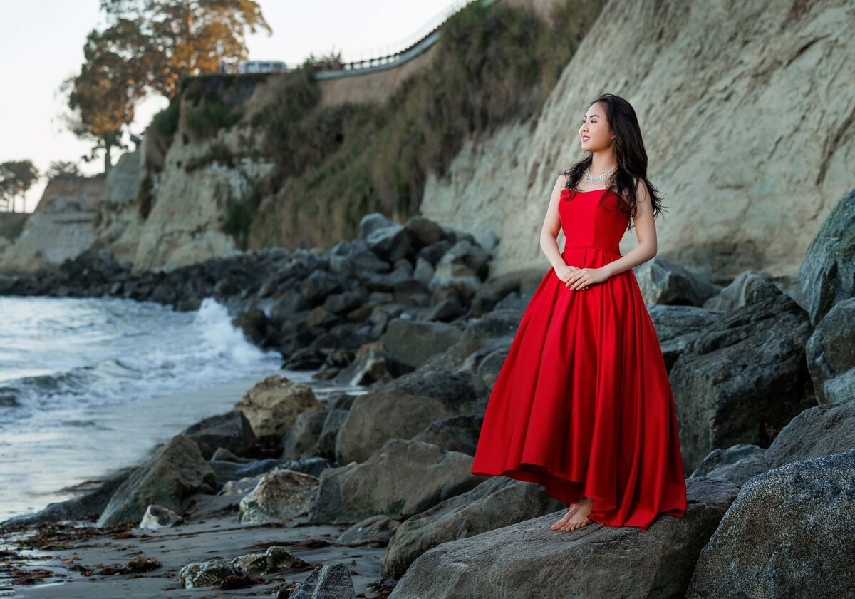 Girl is standing on the rocks during a photoshoot in Capitola by a senior photographer