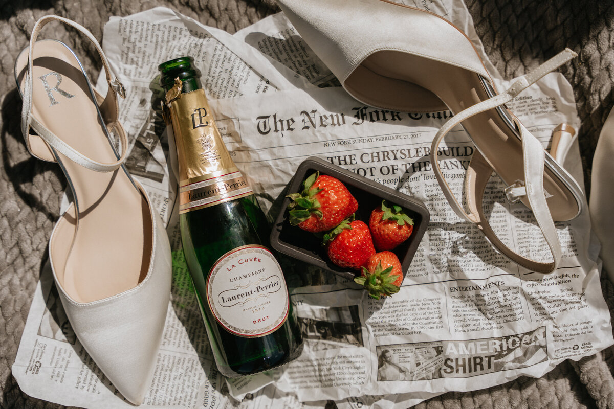 Picnic details with champagne, strawberries, shoes, and bouquet
