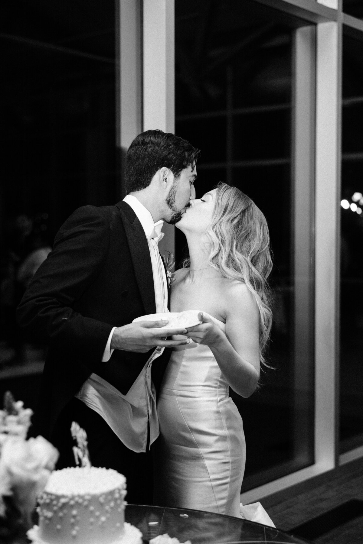 bride and groom kiss after cutting cake