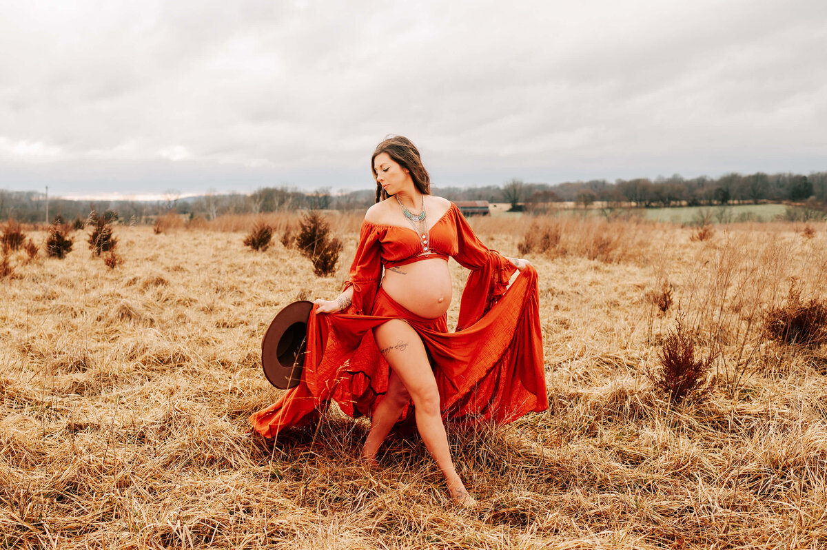 maternity photo in Springfield MO of pregnant mom holding her red dress as she walks