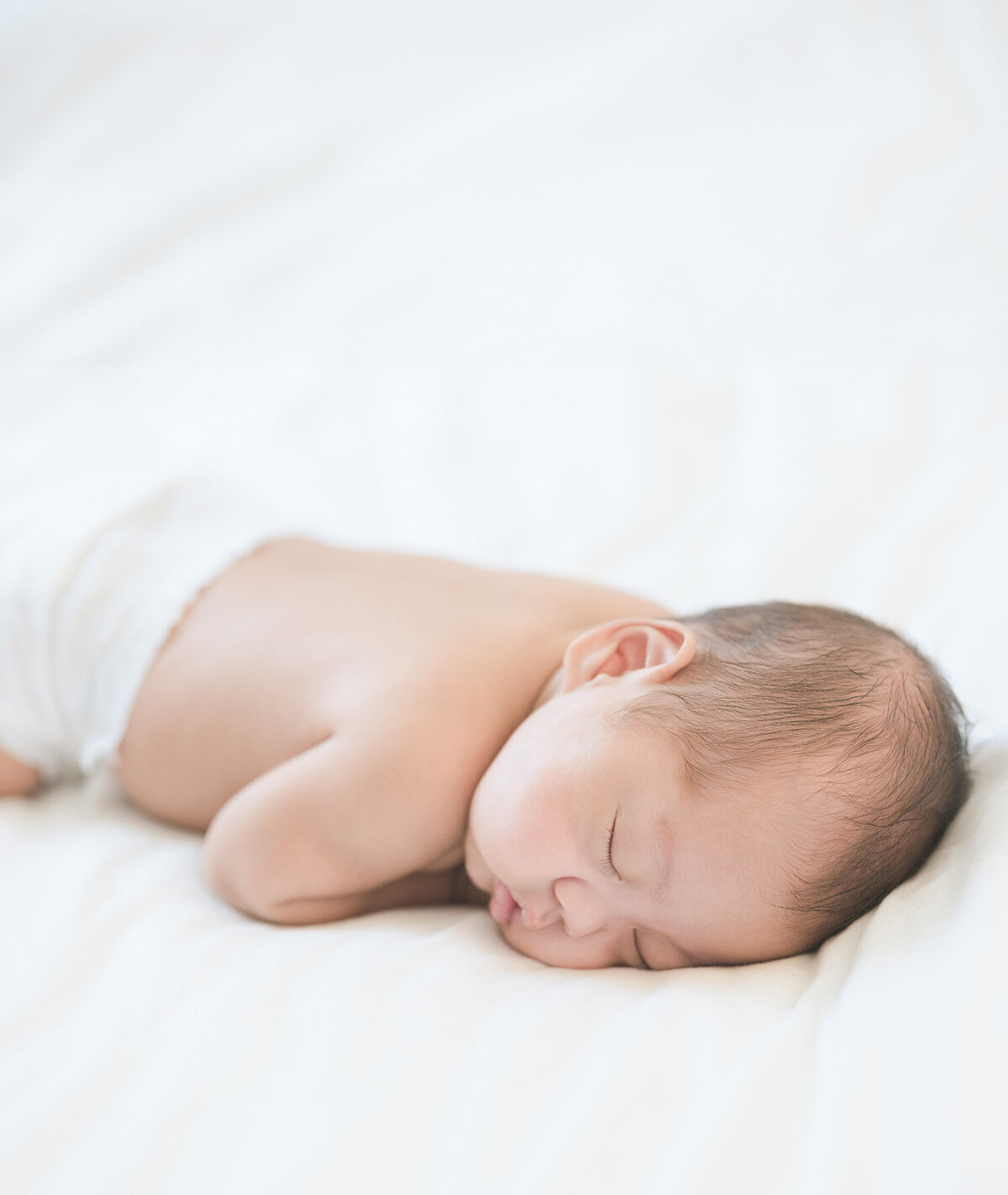 Peaceful newborn baby sleeping on a white blanket, photographed by the best newborn photographer in Los Altos